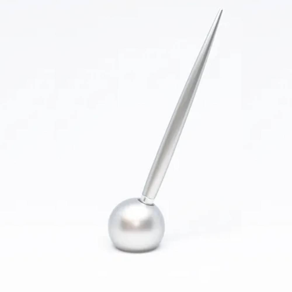 Delight Labo Sand Silver Ballpoint Pen standing upright in its matching elegant metal stand on a desk