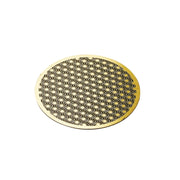 Solid brass coaster with intricate Japanese Asanoha hemp leaf pattern on a dark wooden surface