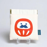 Handcrafted white Shirakawa cotton drawstring pouch featuring a red traditional Daruma amulet charm.